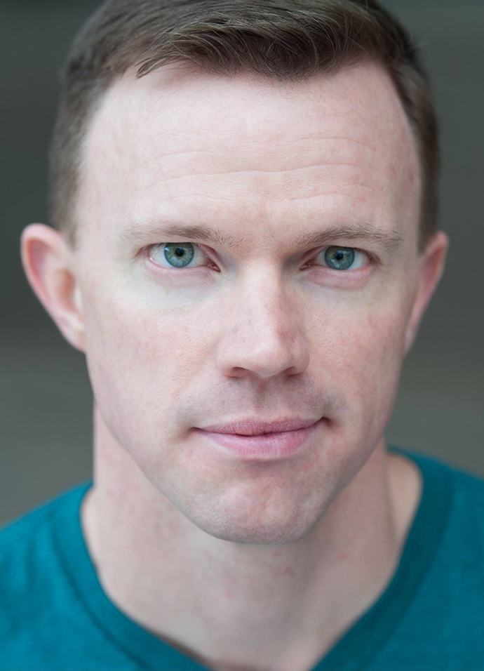 Headshot of a man wearing an aqua T-shirt.