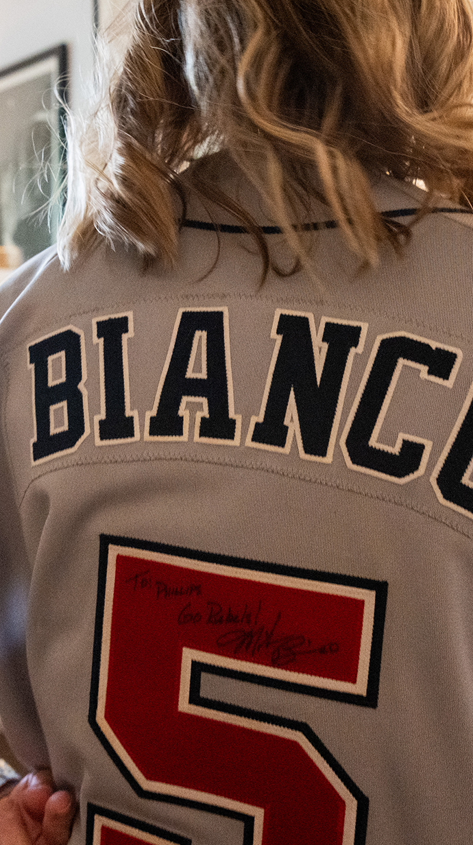 A woman wears a baseball reading 'Bianco.'