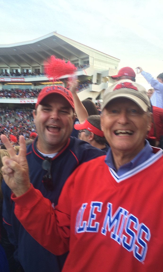 Two men cheer in a football stadium.
