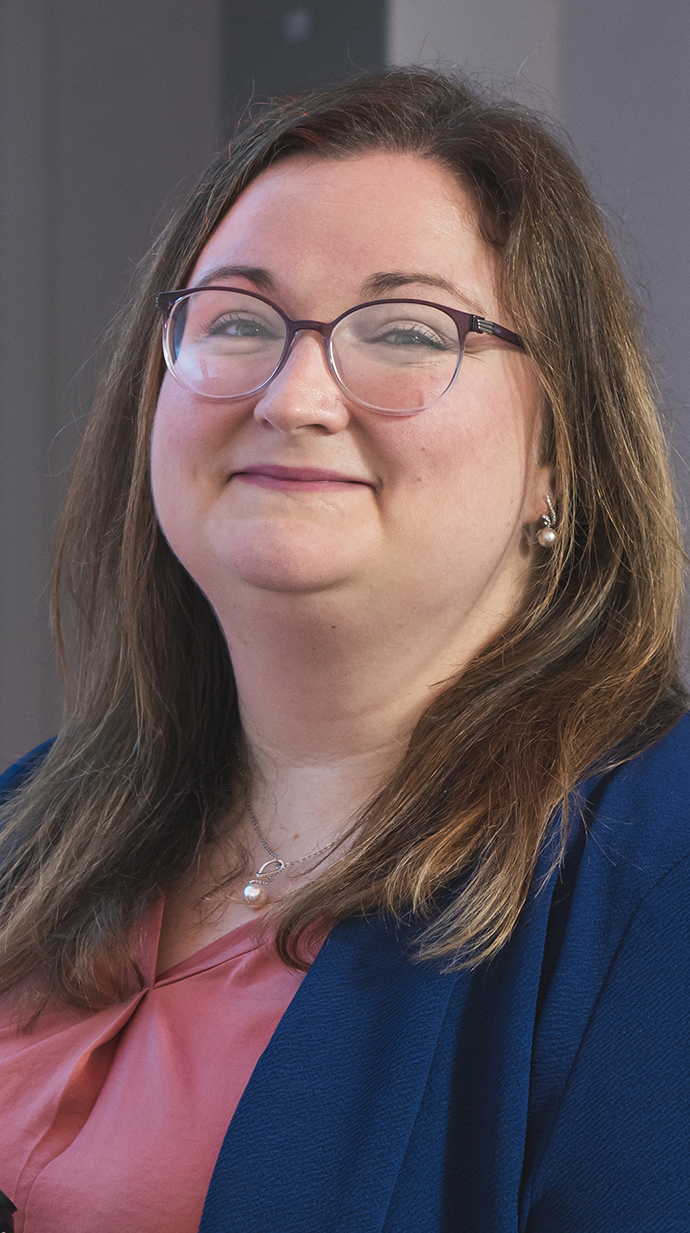 Headshot of a woman wearing a blue jacket over a pink blouse.