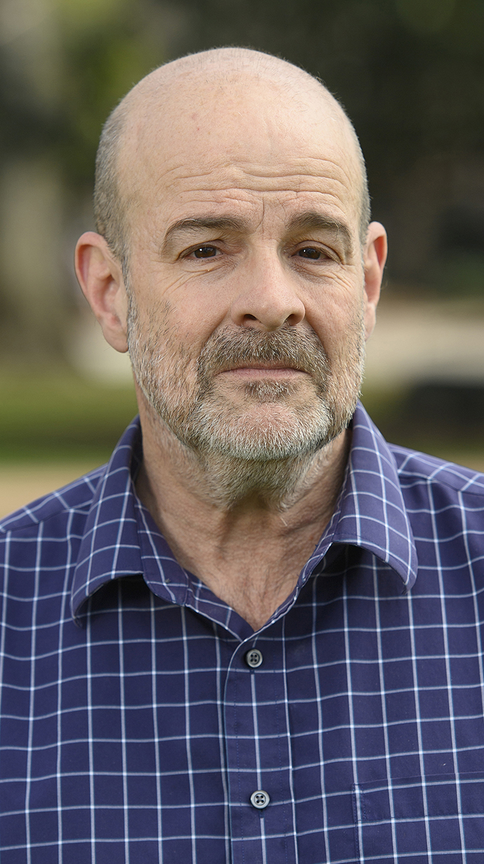 Headshot of a man wearing a blue shirt with white checks.