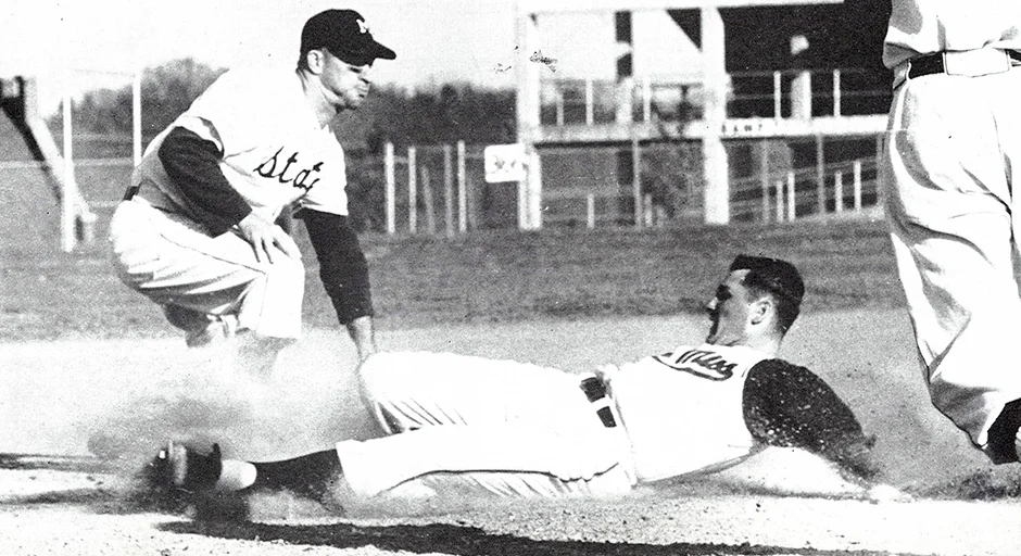 archival photo of baseball players; one person kneeling at base and the other person sliding into the base