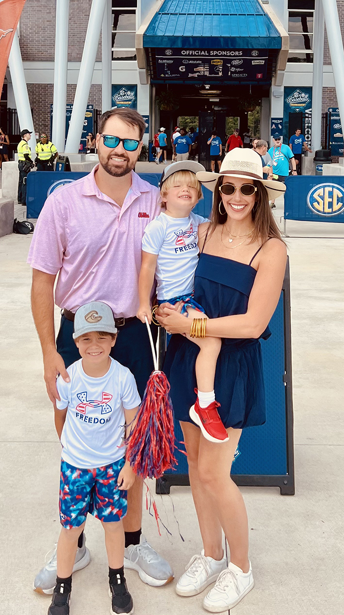 A man, a woman and two young boys stand outside a stadium.