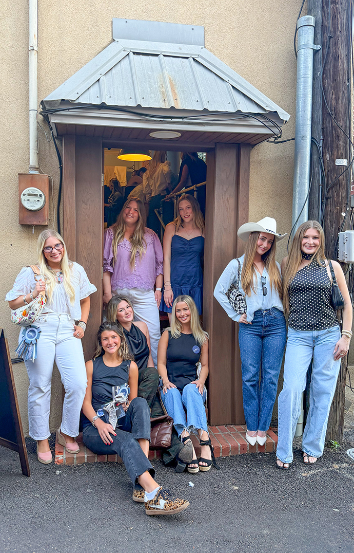 A group of young women stand in the doorway of a retail store in an alley.