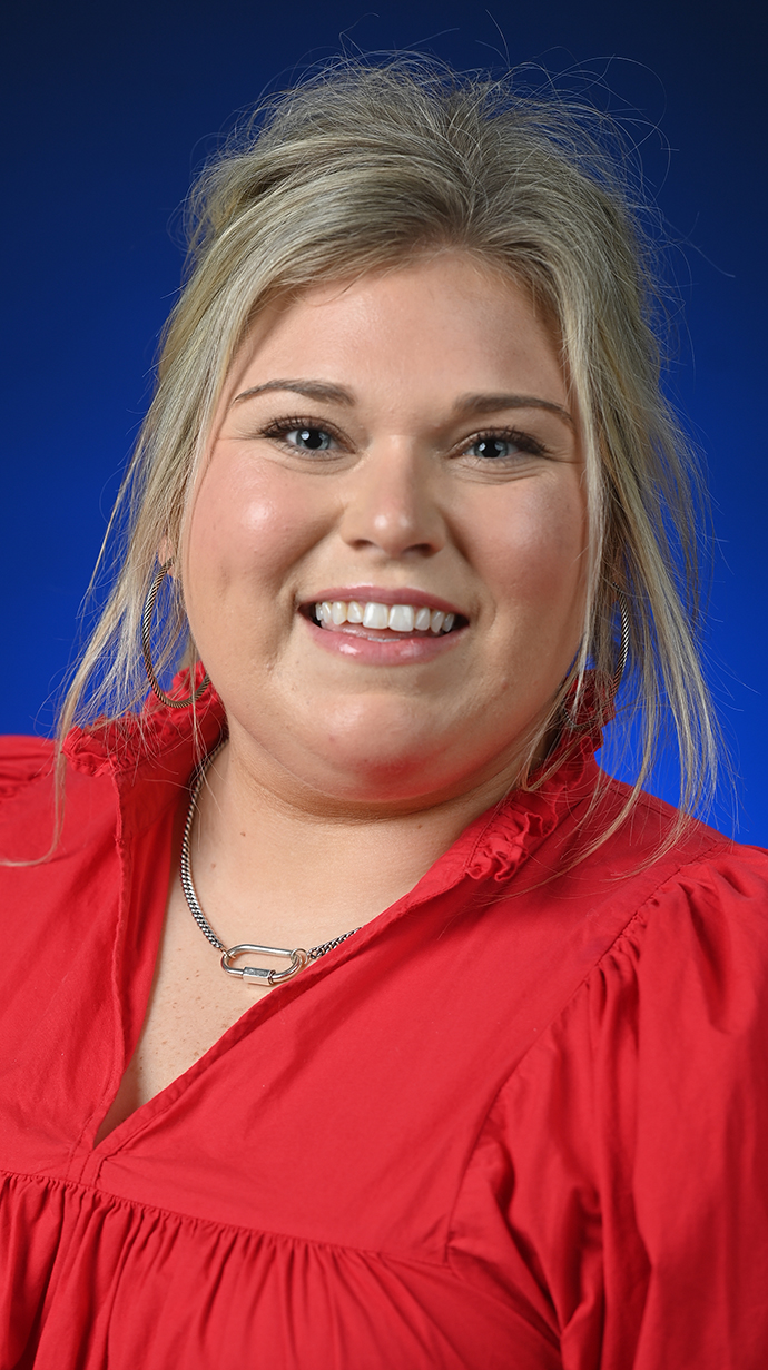 Headshot of a woman wearing a bright red blouse.