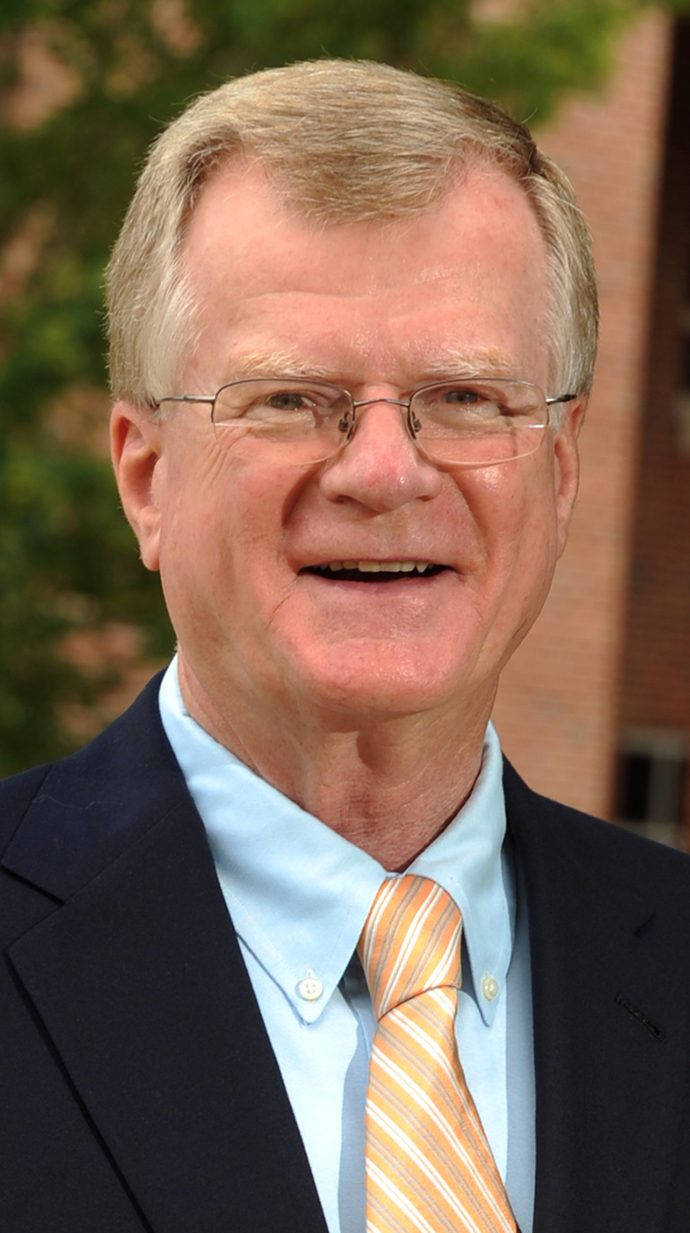 Headshot of a man wearing a suit standing outdoors.