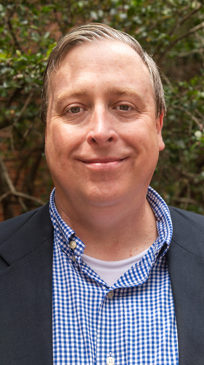 Headshot of a man wearing a blue backet over a blue shirt.