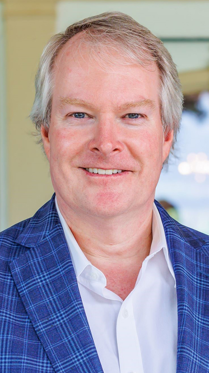 Headshot of a man wearing a blue plaid kacket over an open-collared dress shirt.