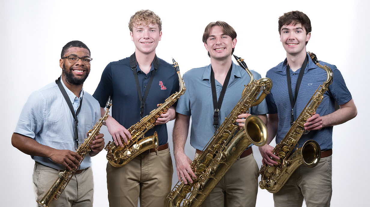Four young men hold saxophones.