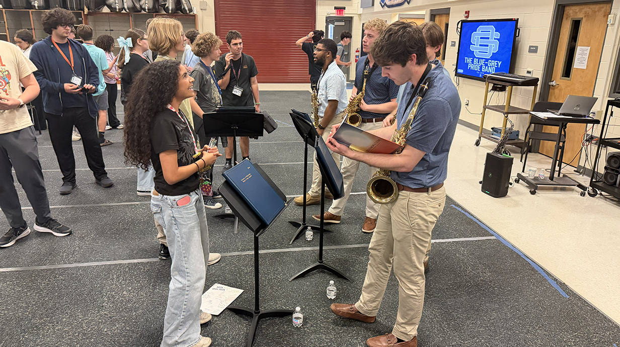 Four young men with saxophones talk with young people after a performance.
