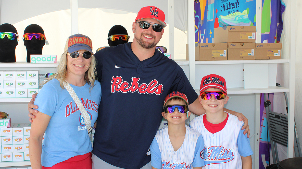 A man, a woman and two boys, all wearing Ole Miss apparel, stand in a souvenir kiosk.