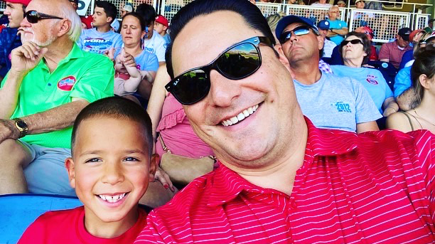 A man and a young boy sitting in an area take a selfie.