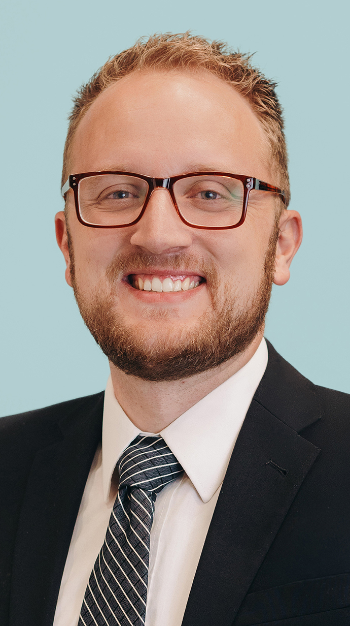Headshot of a man wearing glasses and a dark suit.