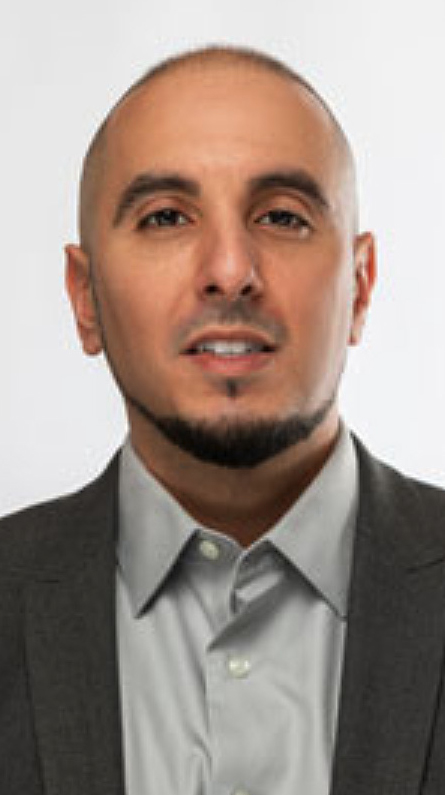 Headshot of a man wearing a dark gray jacket over a gray dress shirt.