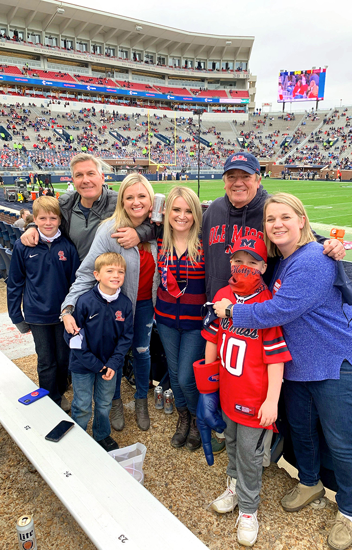 A large family stands in the seating area of a football stadium.