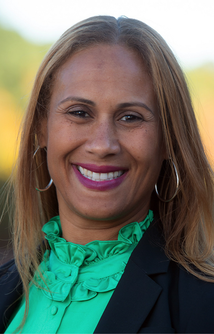Headshot of a woman wearing a black jacket over a green blouse.