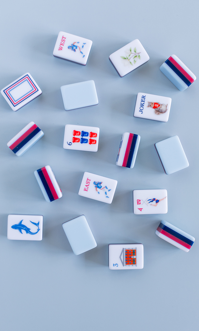 A collection of mahjong tiles are decorated in red and blue and Ole Miss-themed designs, including the Lyceum, a football player, a twirler, a squirrel and Grove trash cans.