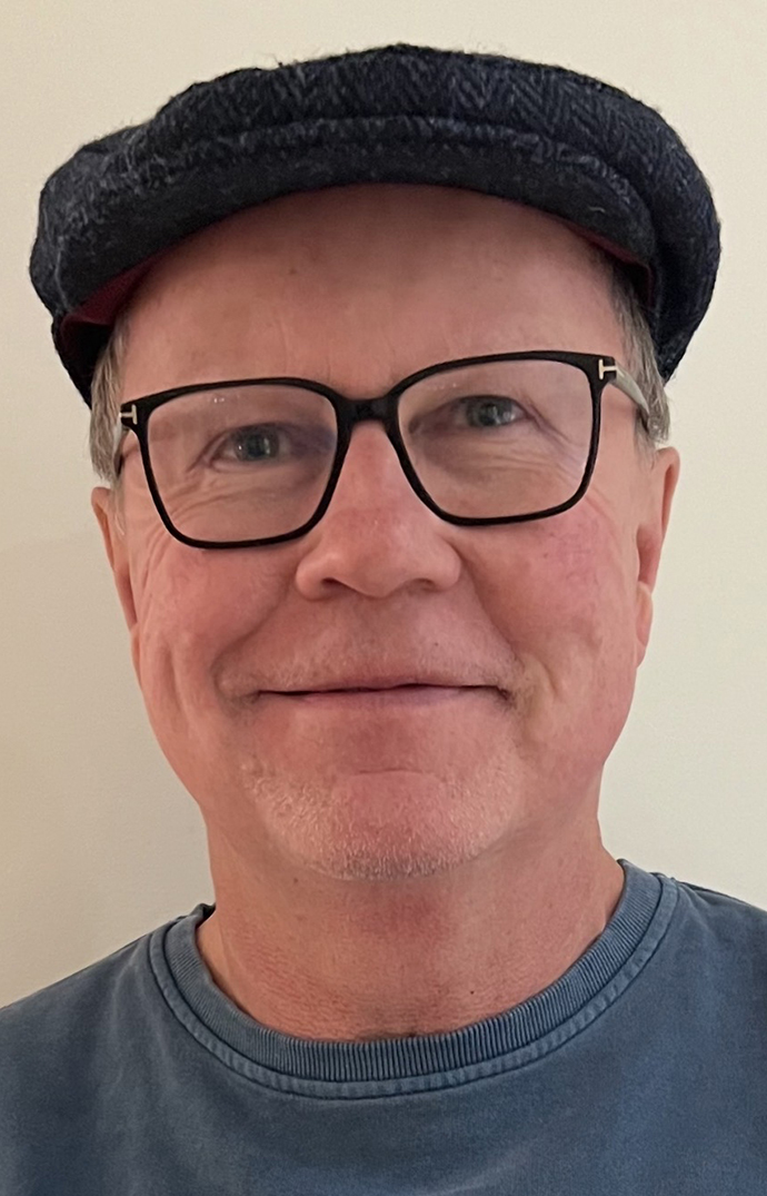 Headshot of a man wearing glasses and a cap.