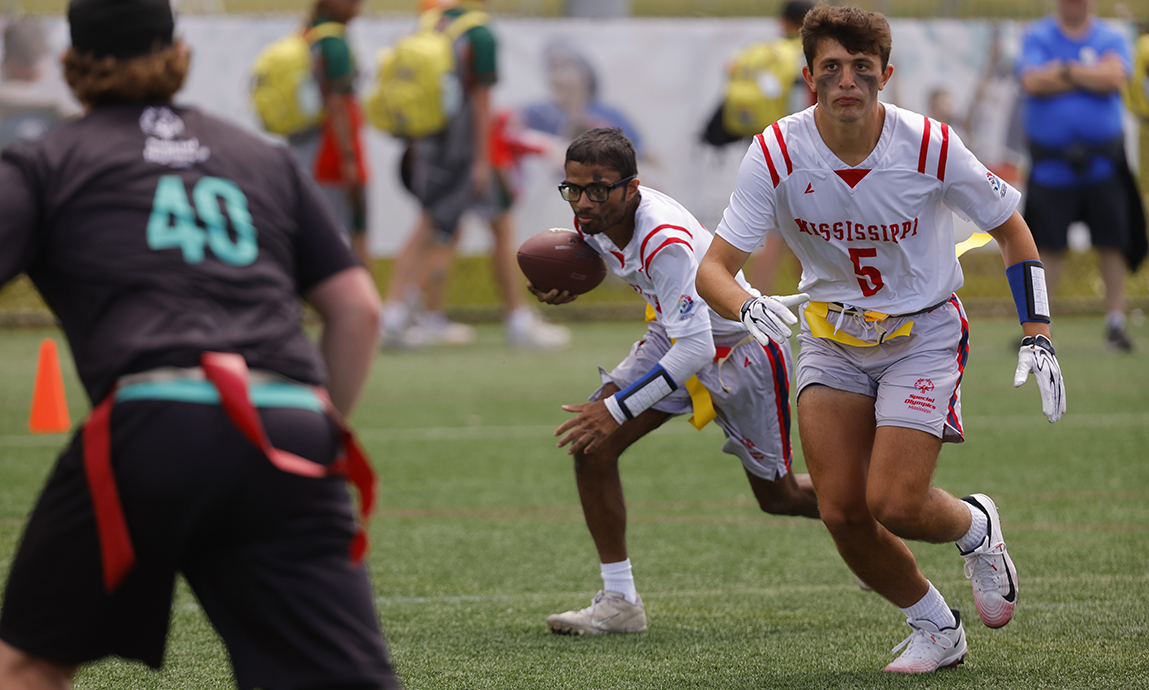 A football player runs with the ball while another player blocks.