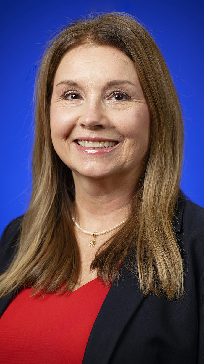 Headshot of a woman wearing a blue blazer over a red clouse.