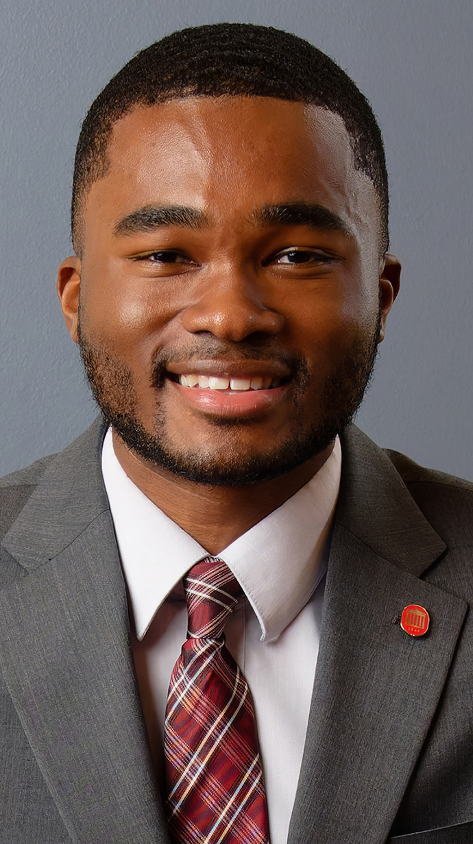 Headshot of a young man wearing a gray suit.