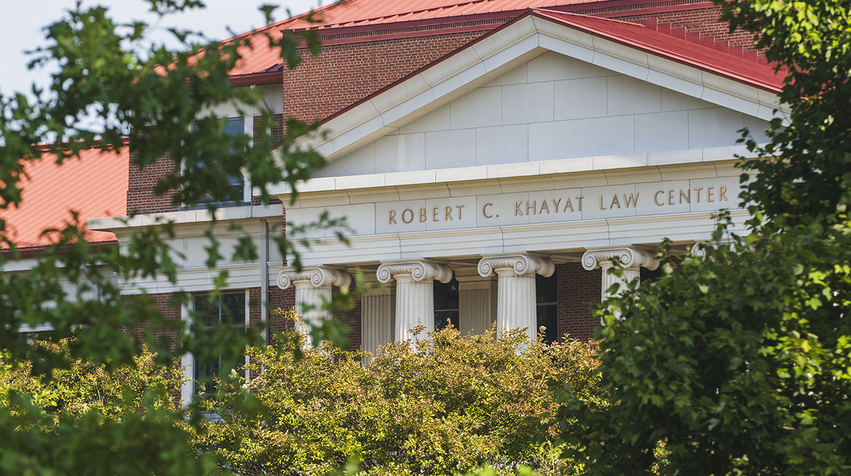 Trees frame a building facade reading 'Robert C. Khayat Law Center.'