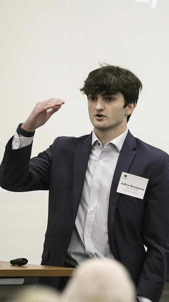 A young man wearing a suit makes a presentation.