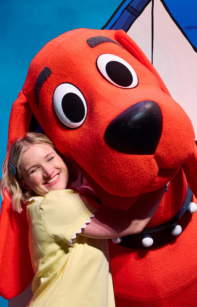 A young woman hugs a costumed character big red dog.