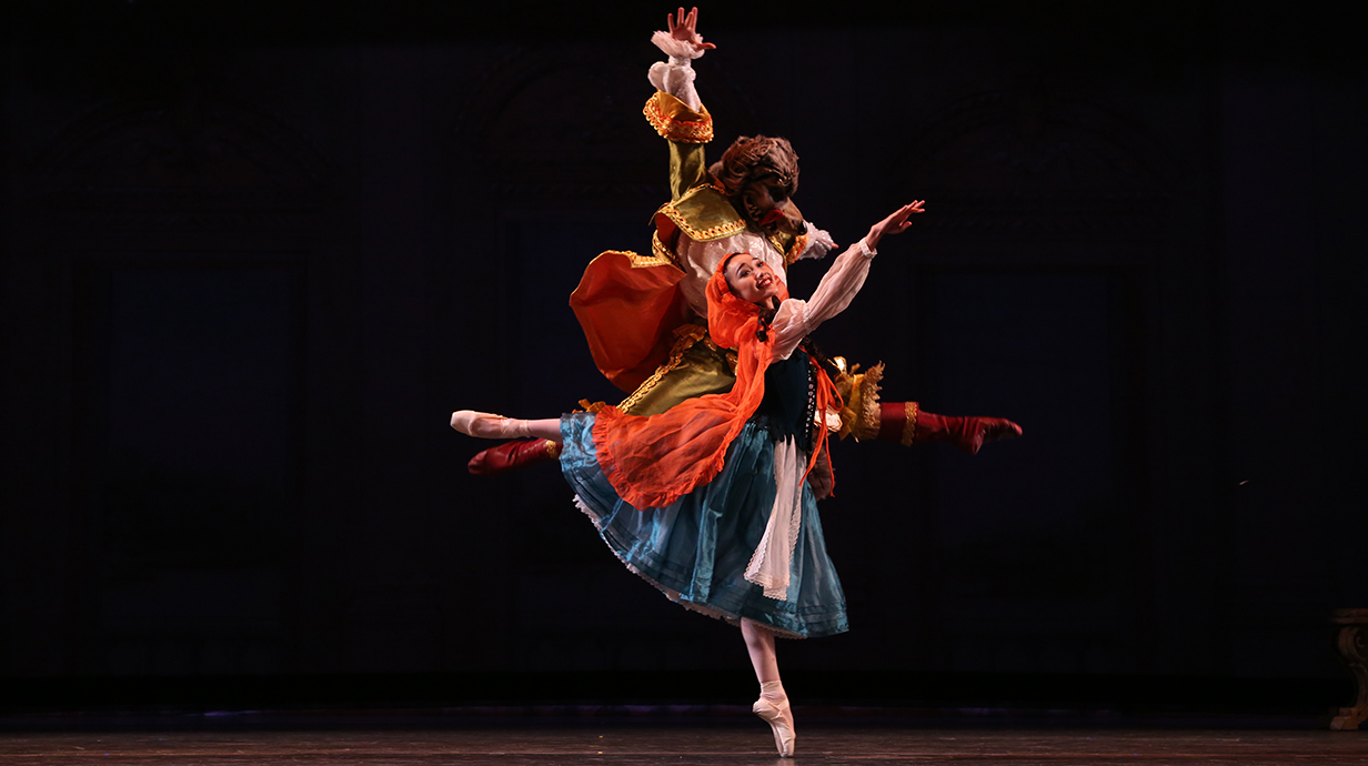 Two costumed characters dance on a stage.