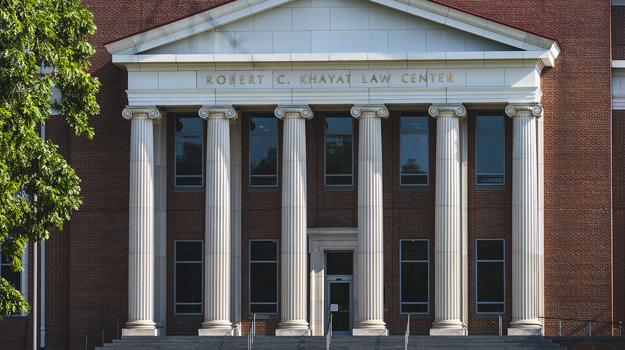 A large brick building with white columns include the name 'Robert C. Khayat Law Center' on its facade.