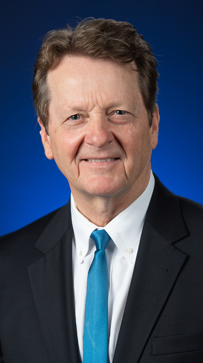 Headshot of a man wearing a dark suit with a turquoise tie.
