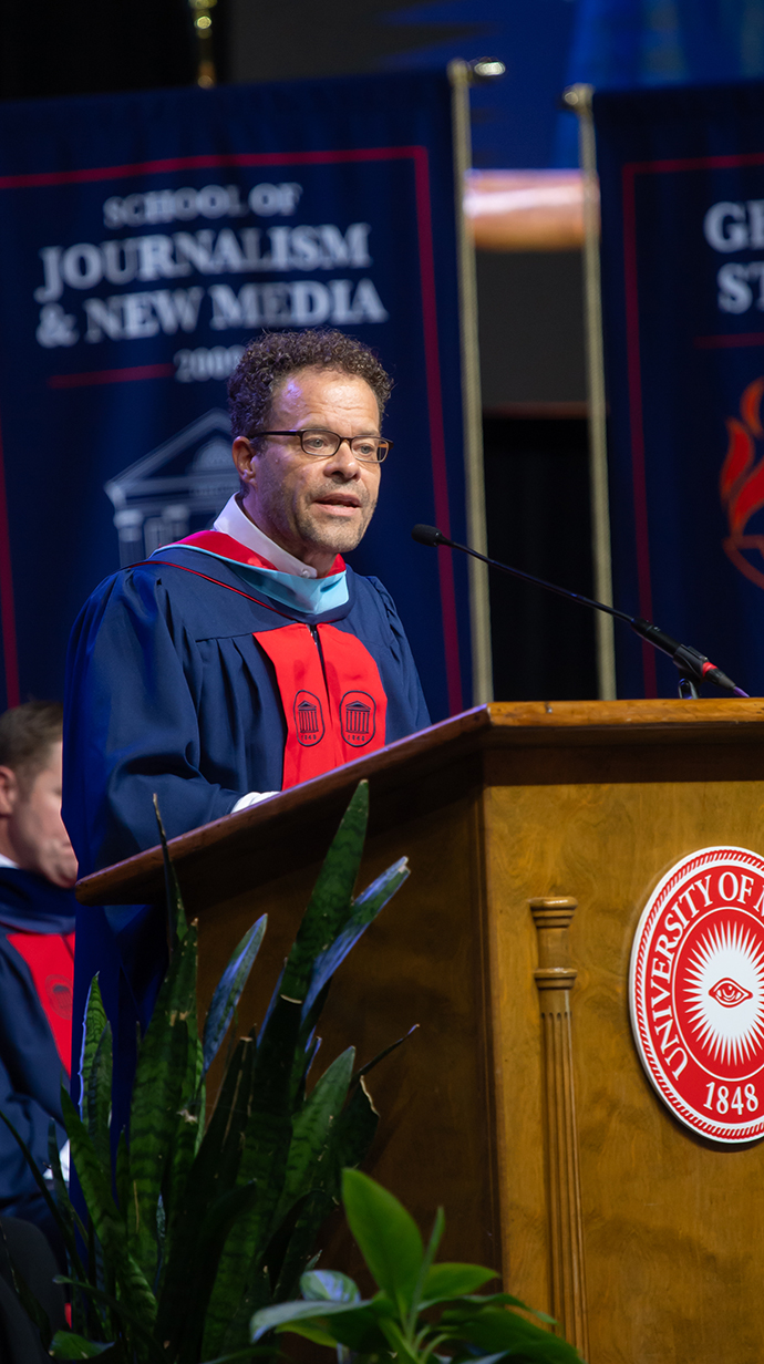 A man speaks at a podium with a University of Mississippi seal on the front.