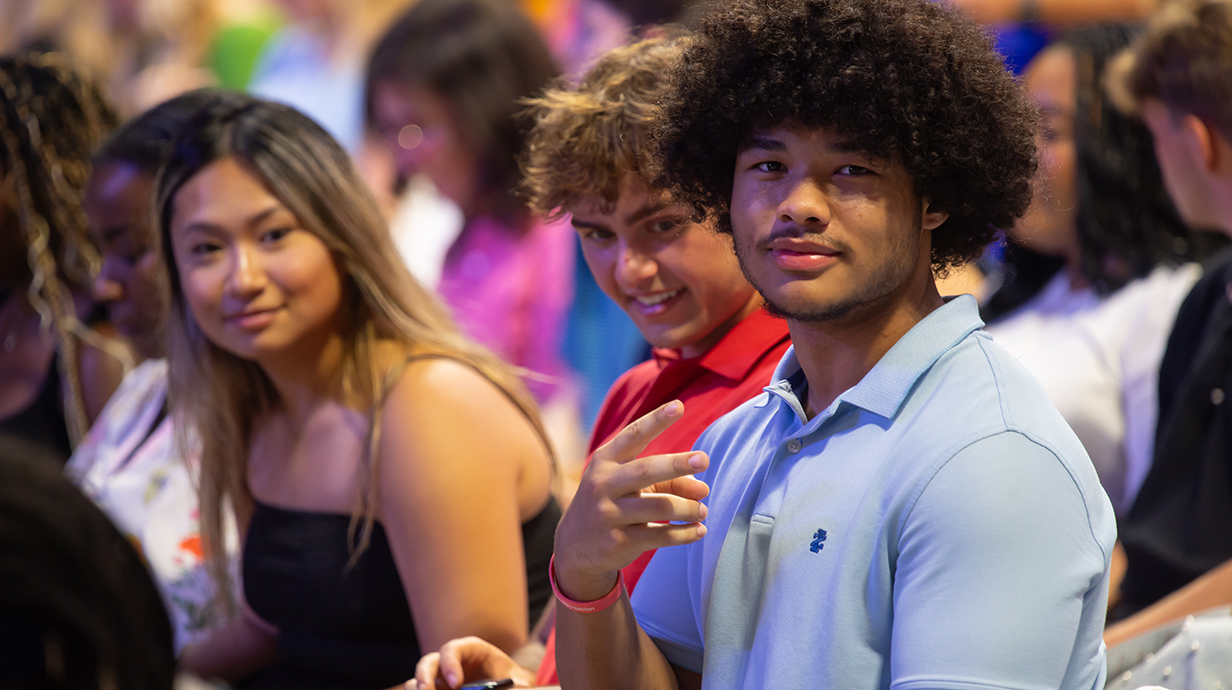 A group of young people sit in an arena.