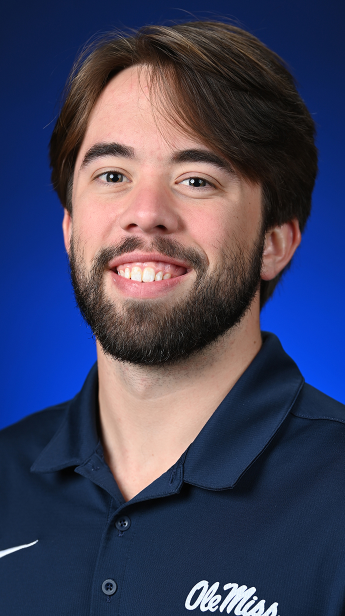 Headshot of a young man wearing a dark blue polo shirt.