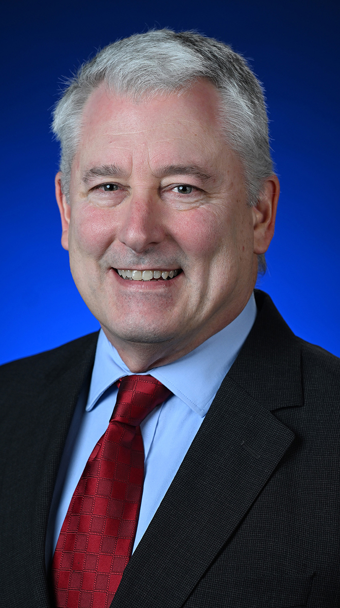 Headshot of a man wearing a dark suit with a dark red tie.