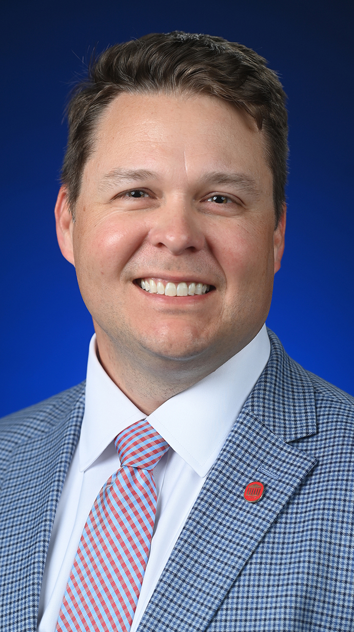 Headshot of a man wearing a light blue suit.
