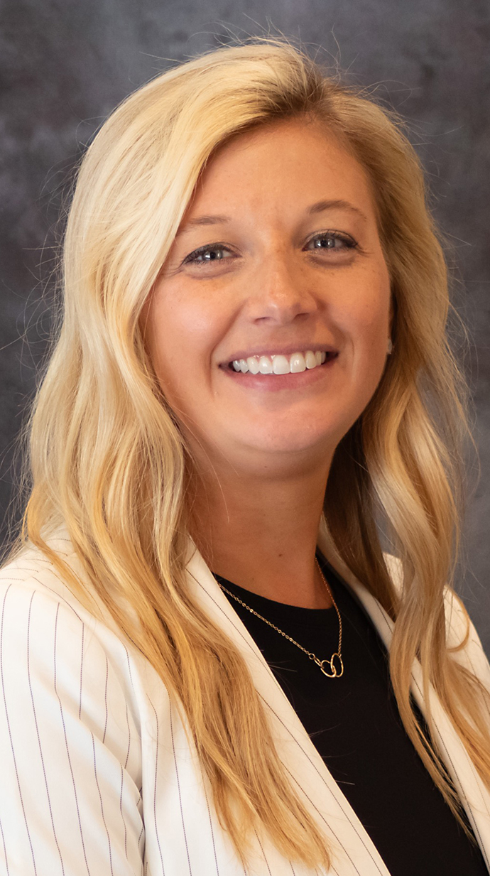 Headshot of a woman wearing a cream-colored jacket over a black blouse.