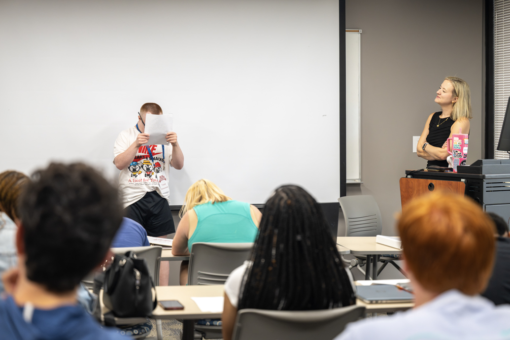 Young man delivers a speech at the front of a classroom.