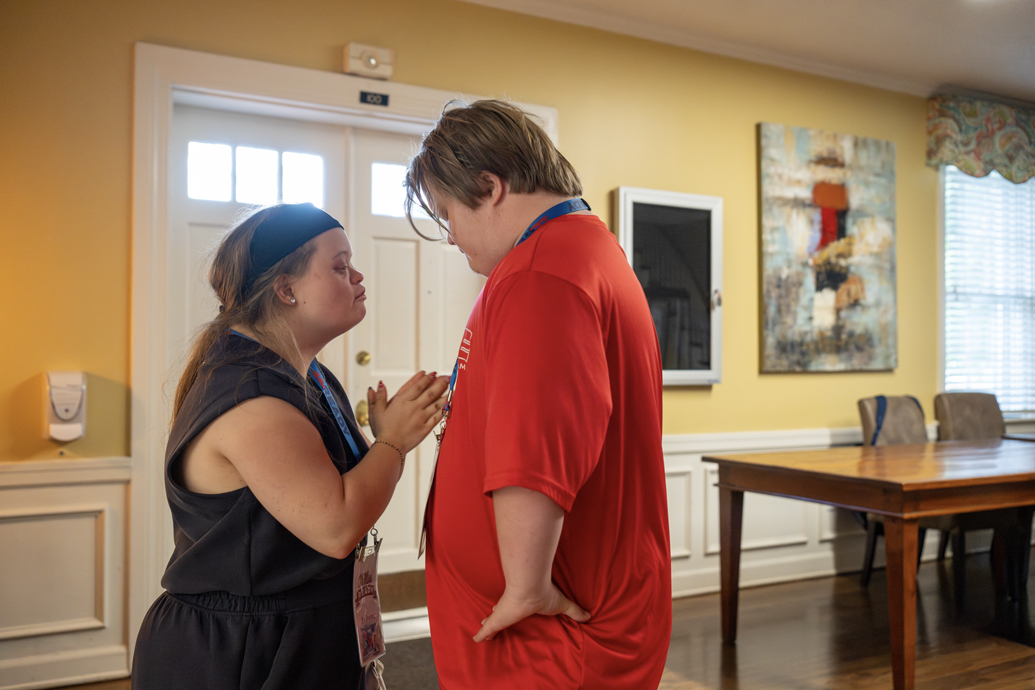 Young man and young woman have a brief exchange while standing in a hallway.