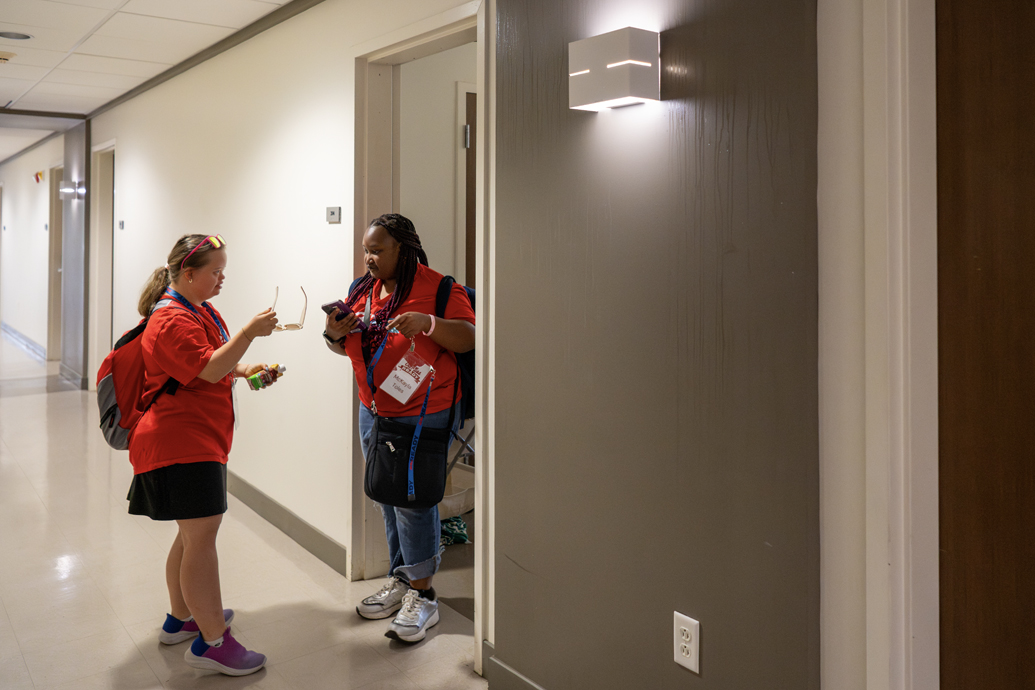 Two young women walk together outside a dorm building.