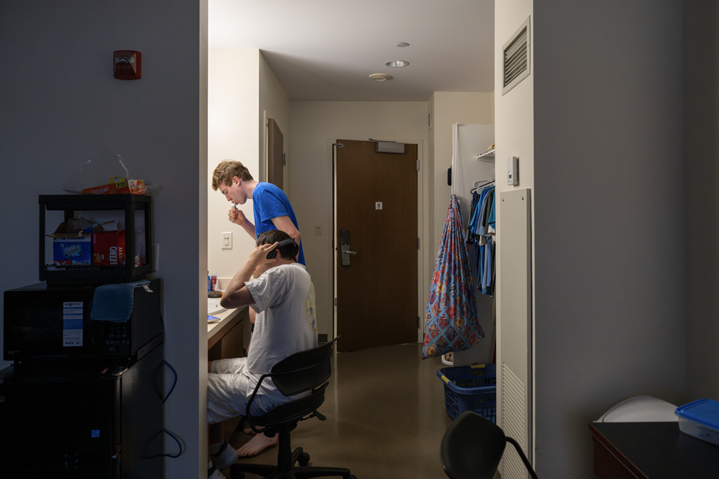 Two young men get ready in a dorm room in the morning.