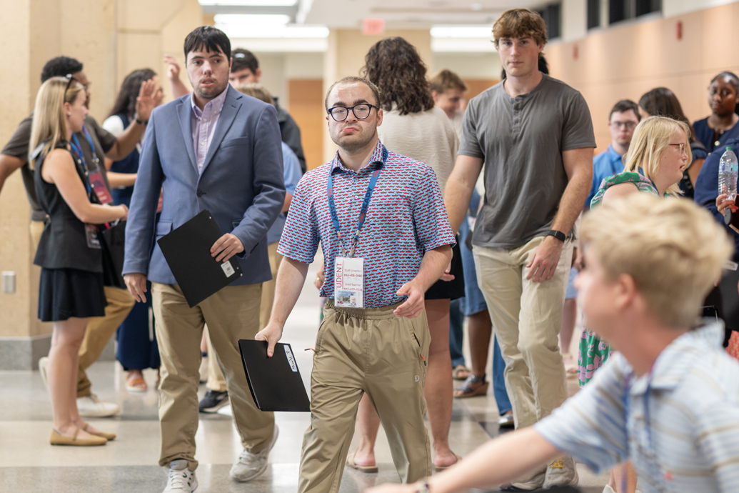 Two young men and a man walk together toward a building entrance.