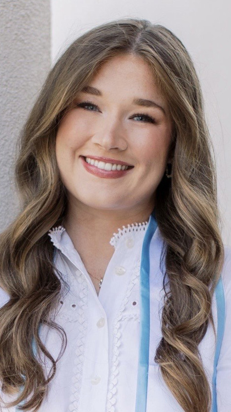 Headshot of a young woman wearing a white blouse with light blue stripes.