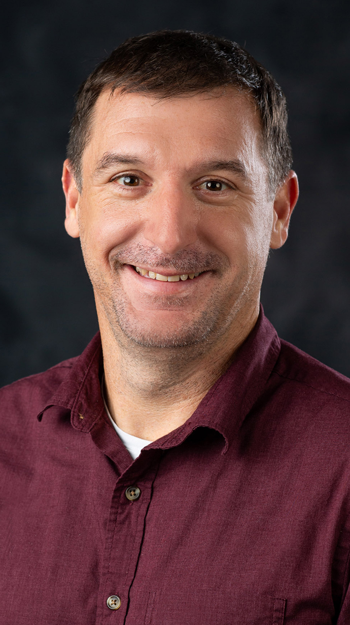 Headshot of a man wearing a maroon shirt.