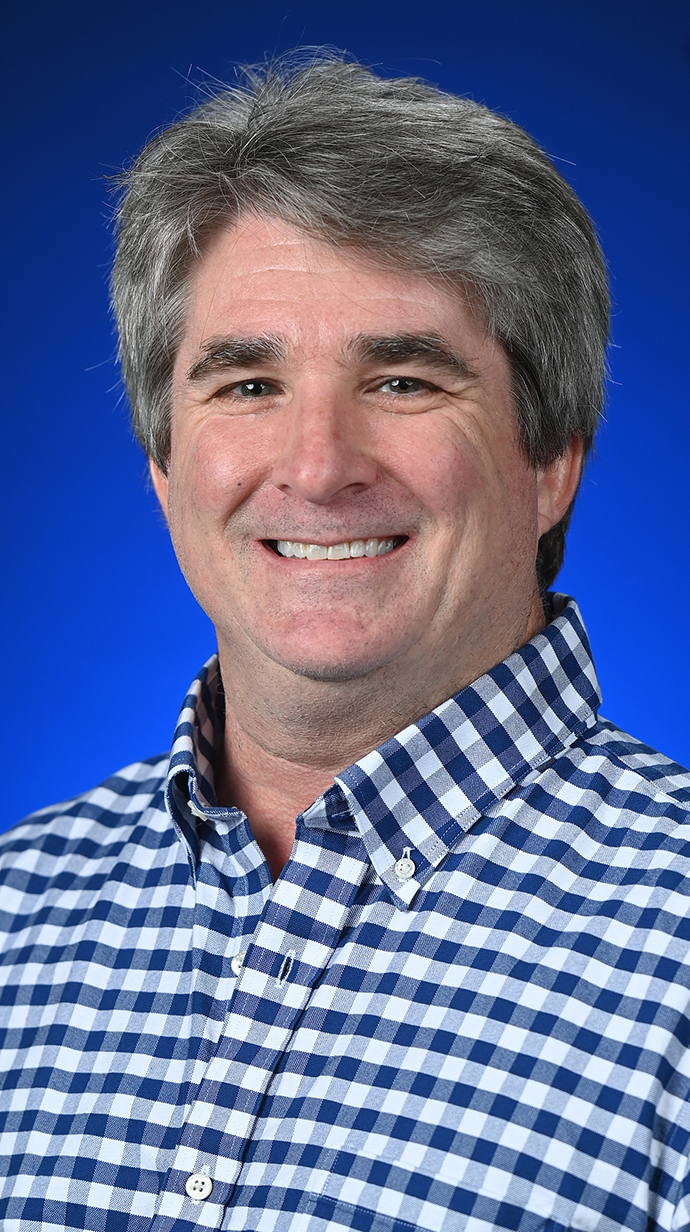 Headshot of a man wearing a blue-and-white dress shirt.