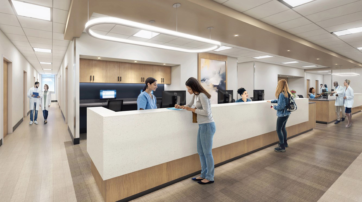 Medical professionals talk at a long counter in a spacious hallway.