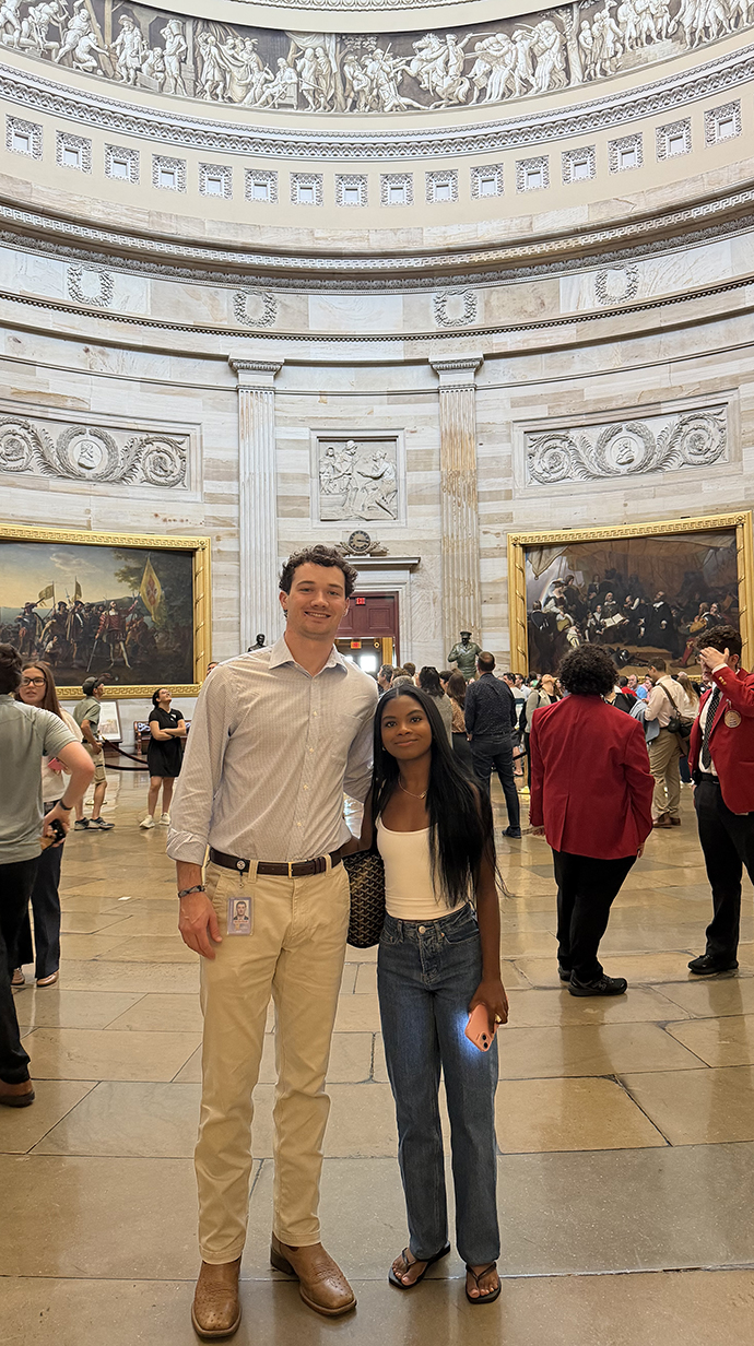 A young man and woman stand inside the U.S. Capitol.