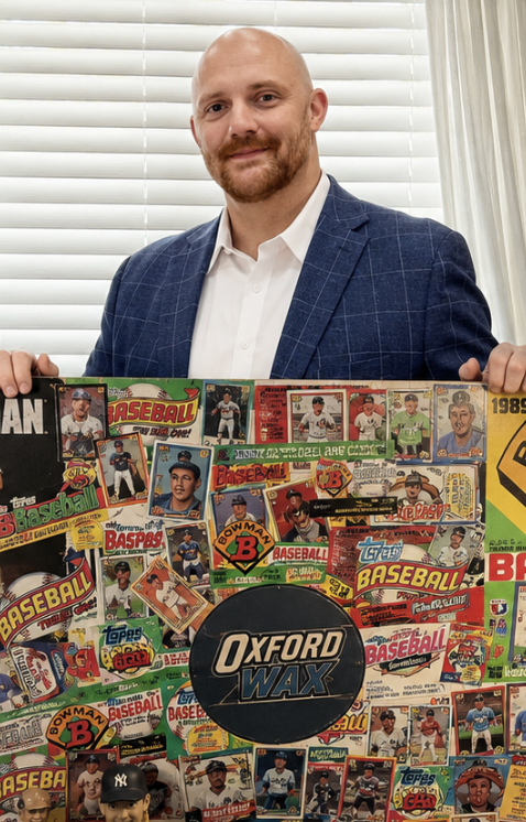 A man holds a display board filled with baseball cards and wrappers.
