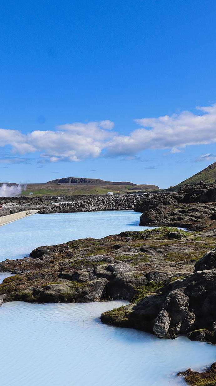 A pond next to a rocky slope is filled with milky blue water.