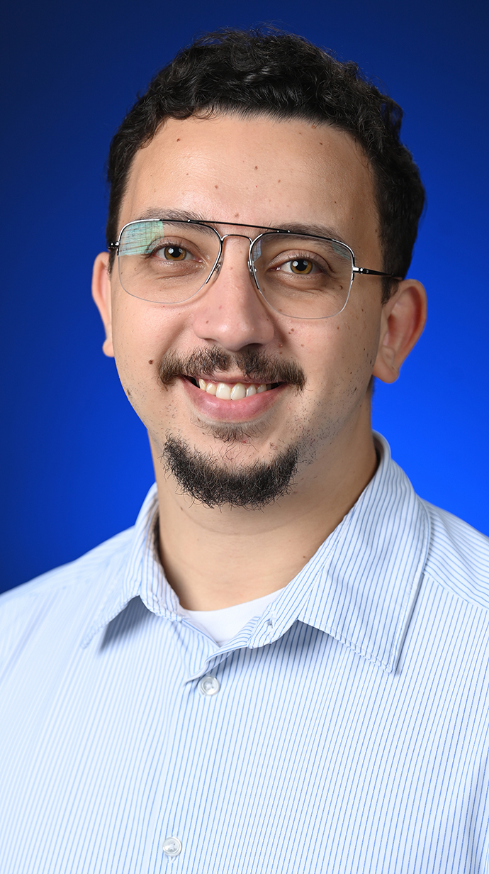 Headshot of a man wearing a blue-and-white striped dress shirt.